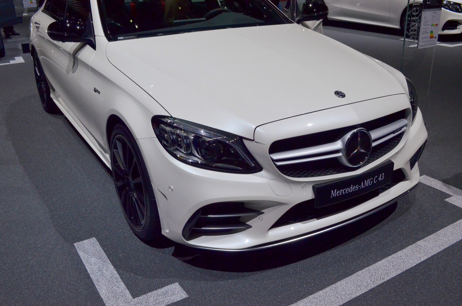 Front close-up of a white car with AMG grille and LED headlights