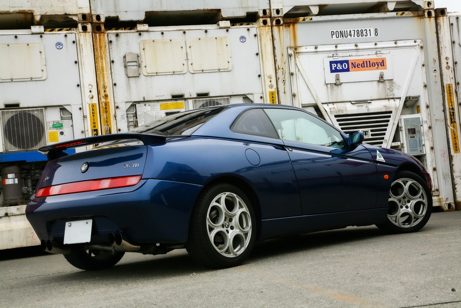 Rear side angle with V6 TB badge and distinctive round-spoke wheels