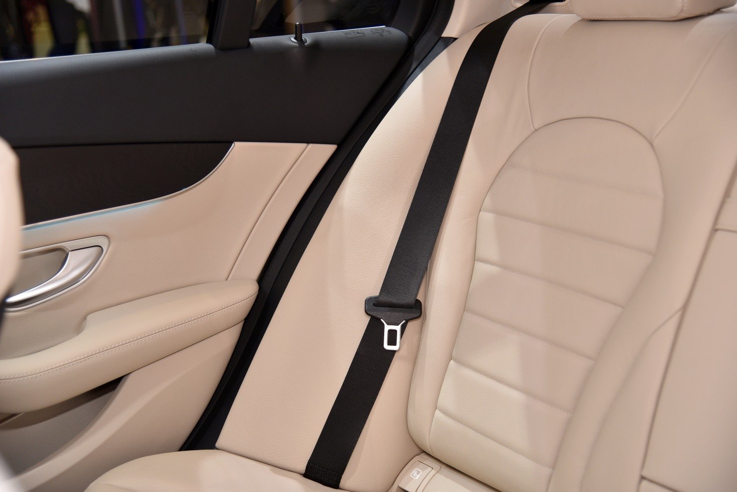 Beige leather rear seat with visible seatbelt and door panel
