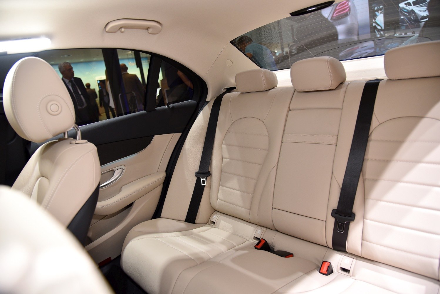 Beige leather rear seats with black seat belts and door interior.