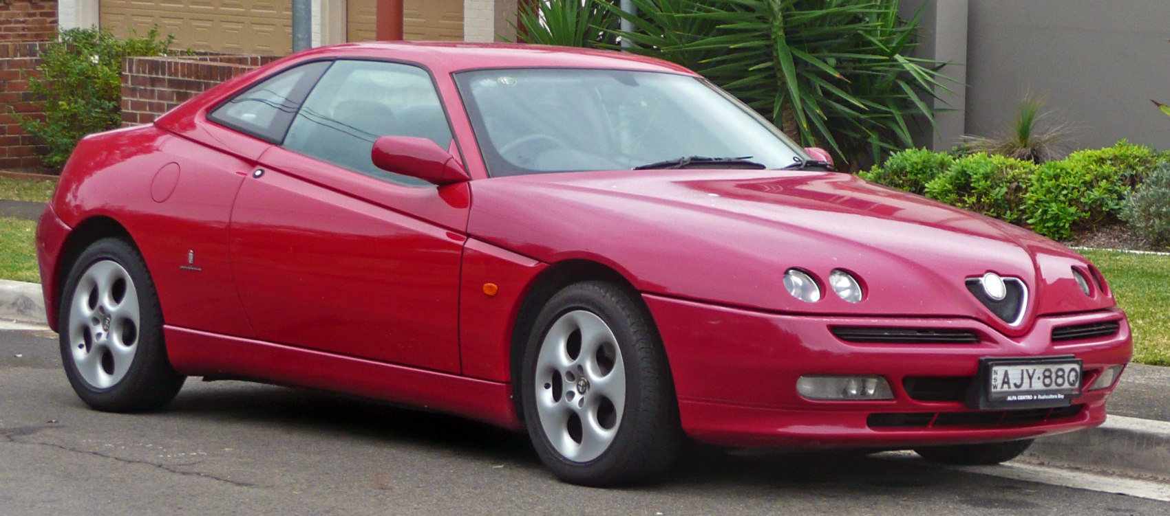 Red coupe with quad round headlights and aerodynamic lines