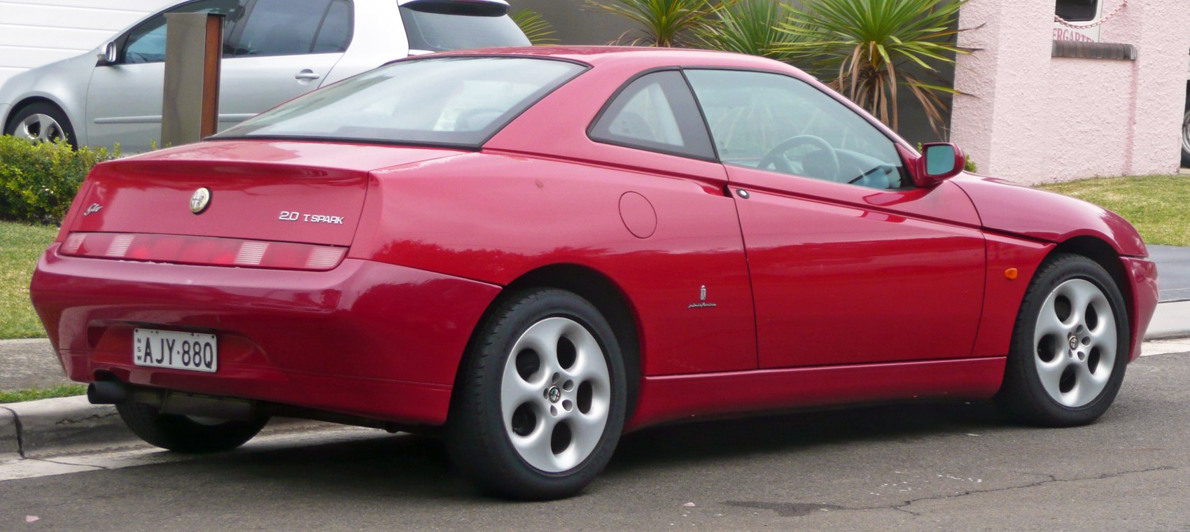 Rear-side view of red coupe with distinct Pininfarina design and unique alloy wheels