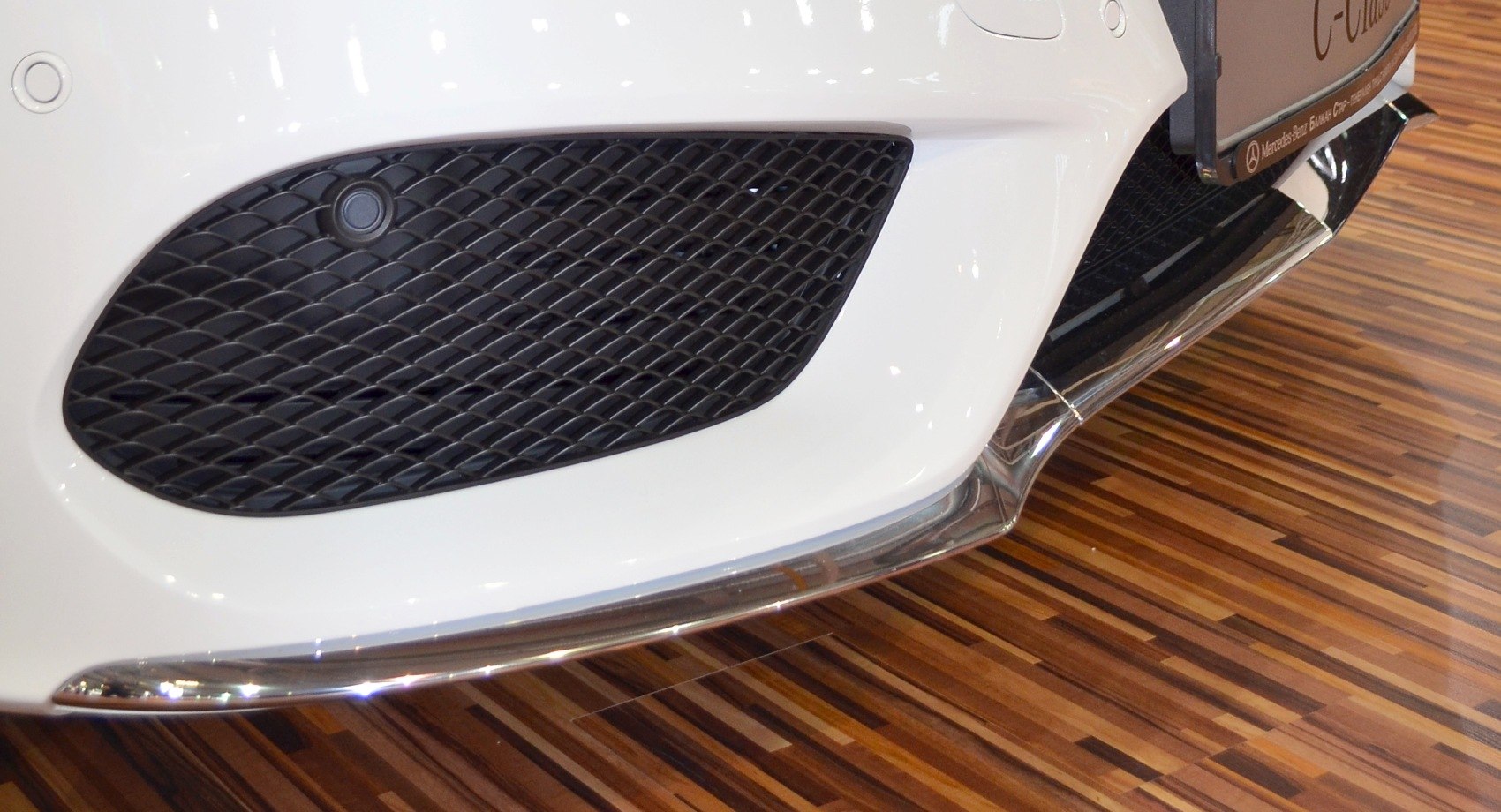 Close-up of front lower bumper with mesh air intake and chrome trim