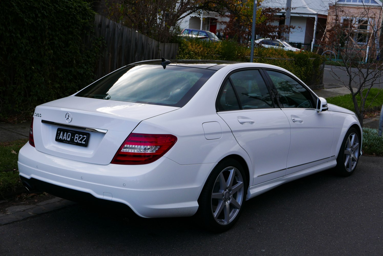 Rear side view of a white sedan with distinctive tail lights and alloy wheels