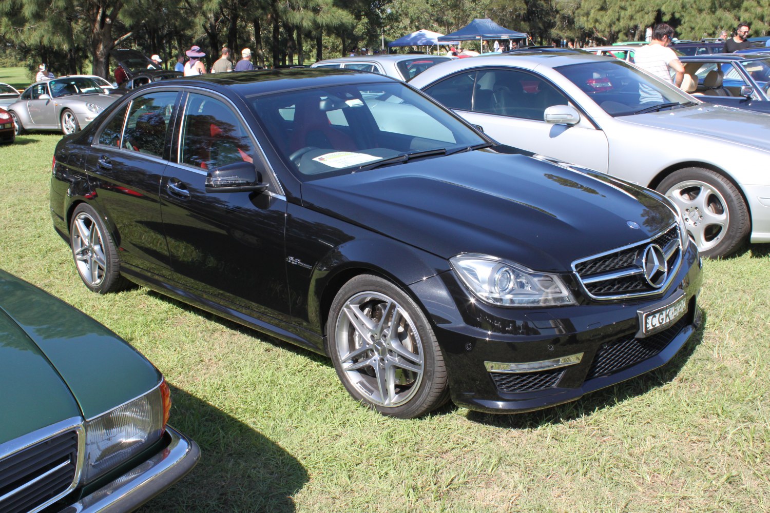 Black sedan with AMG wheels and modern headlights from front side angle