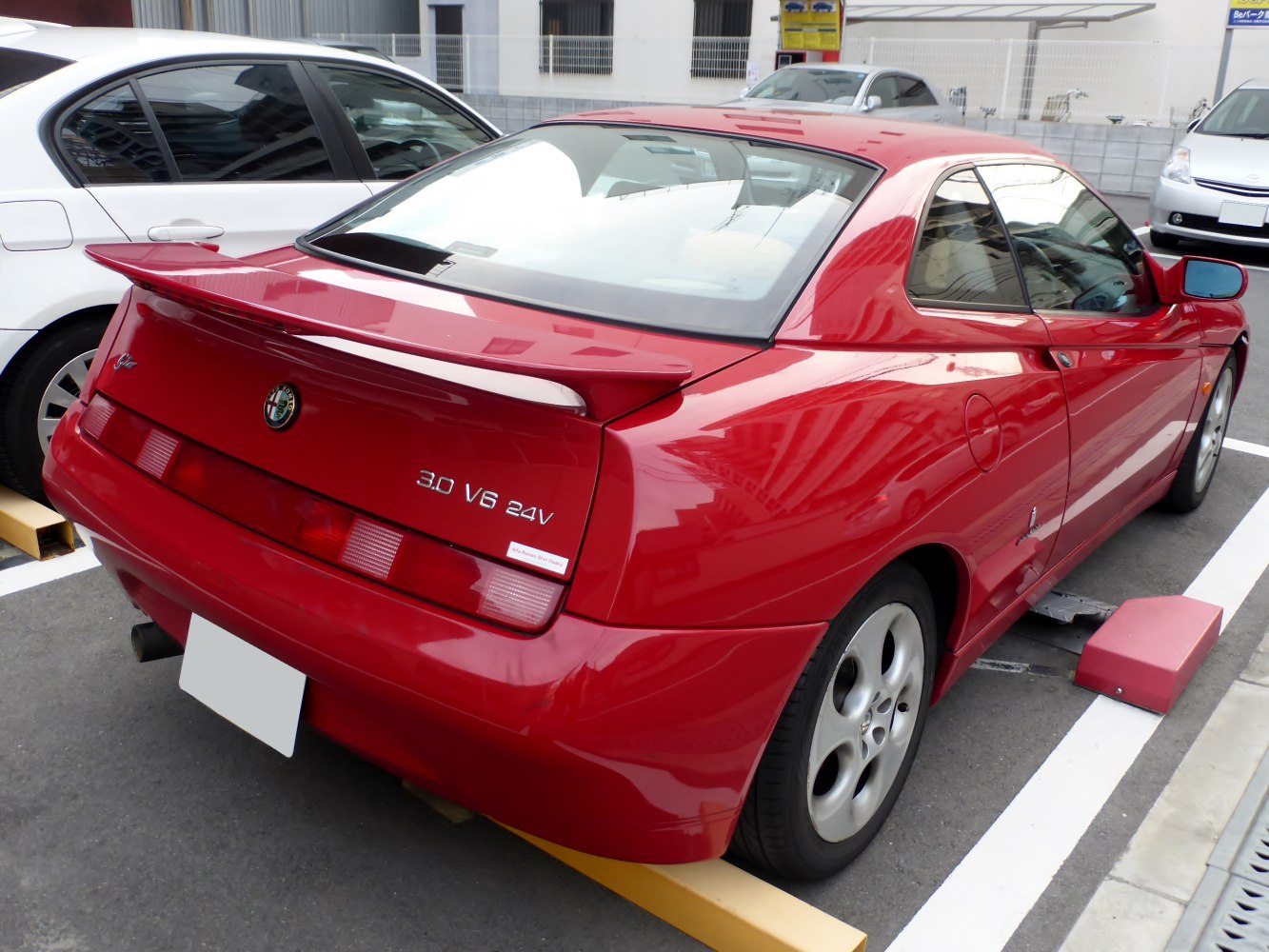 Rear view of red coupe with spoiler and V6 badging