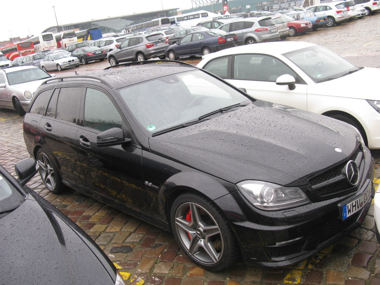Black station wagon with AMG wheels and red brake calipers on wet pavement