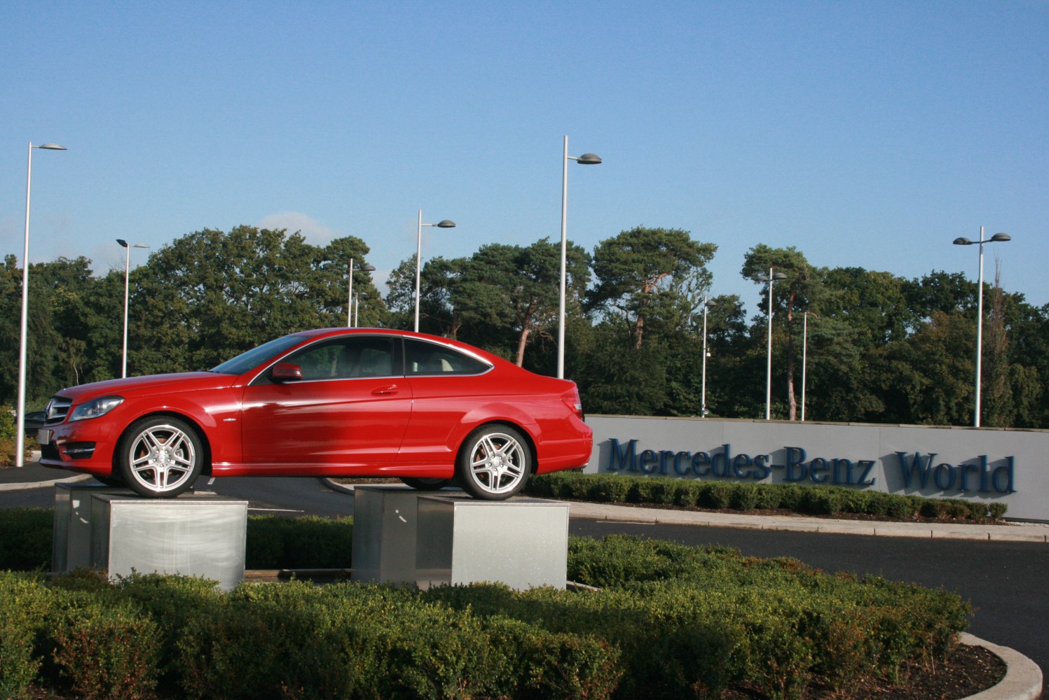 Red coupe side profile with sporty alloy wheels on raised platform