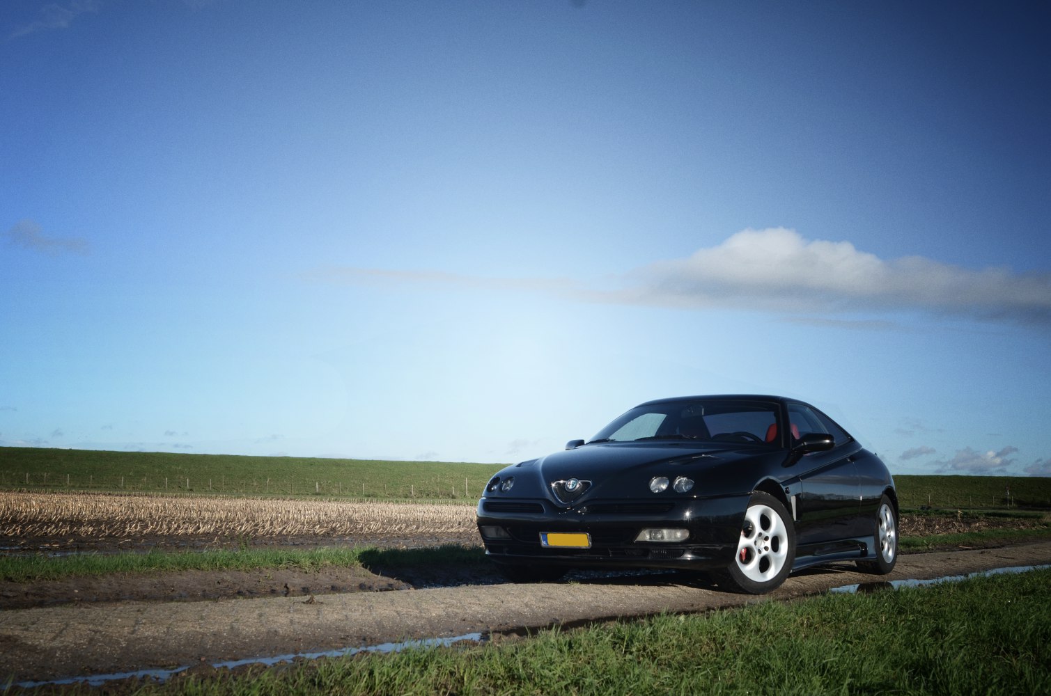 Black sleek coupe with quad headlights on rural road