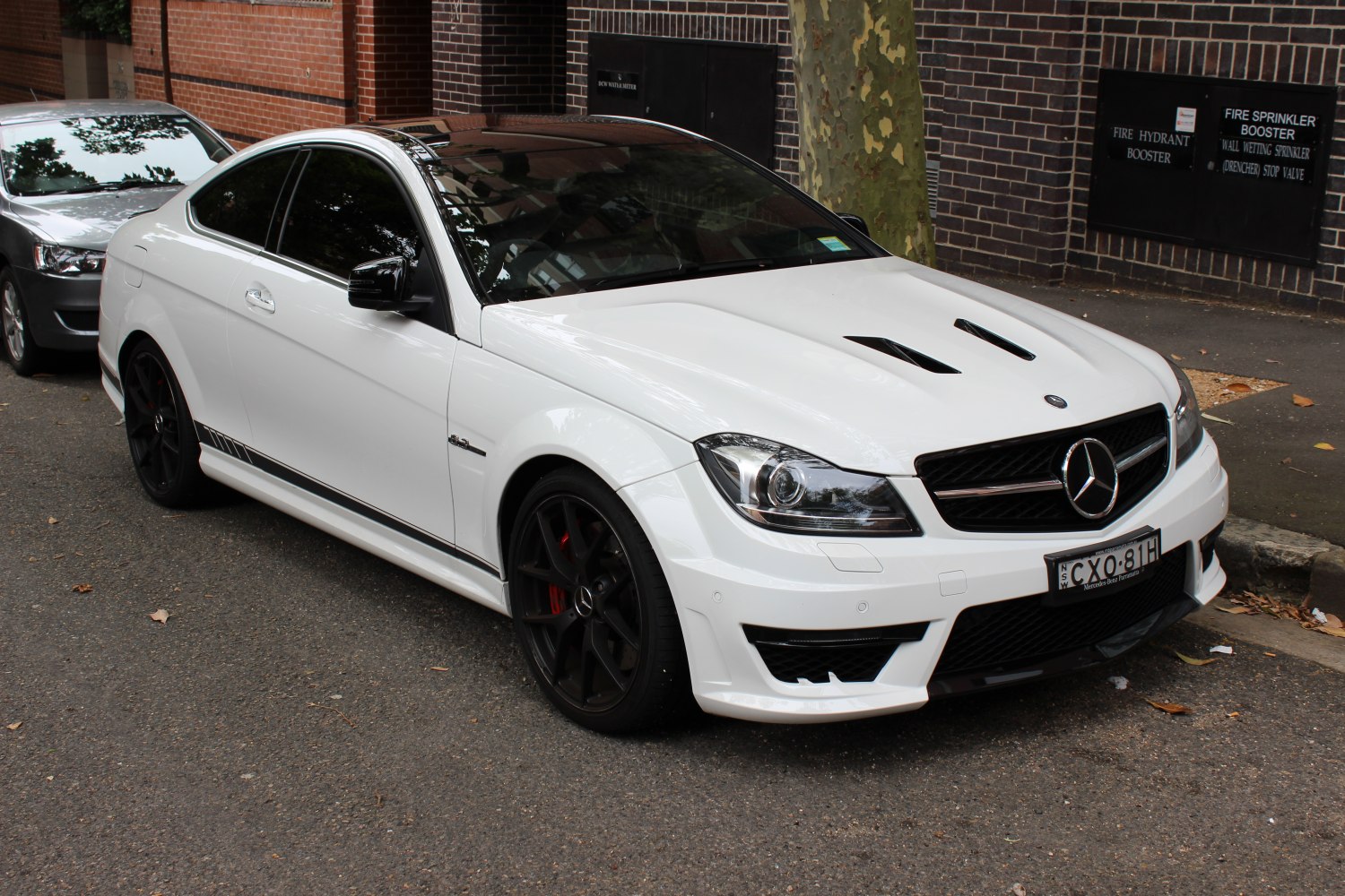White coupe with hood vents and black sport wheels.