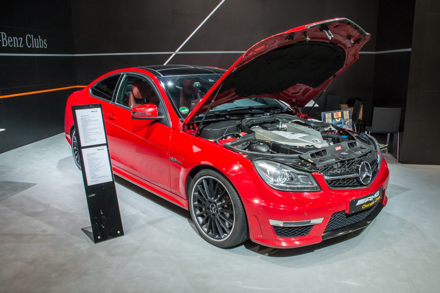 Red coupe with open hood revealing engine and front LED headlights