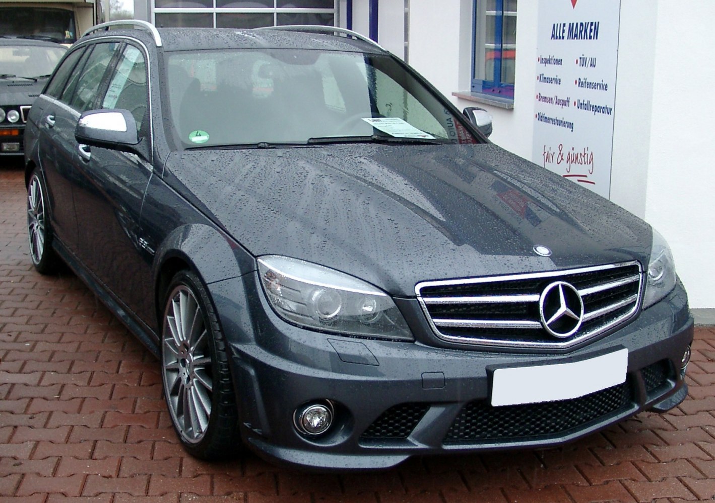 Front view with headlight, grille, and rain droplets on surface