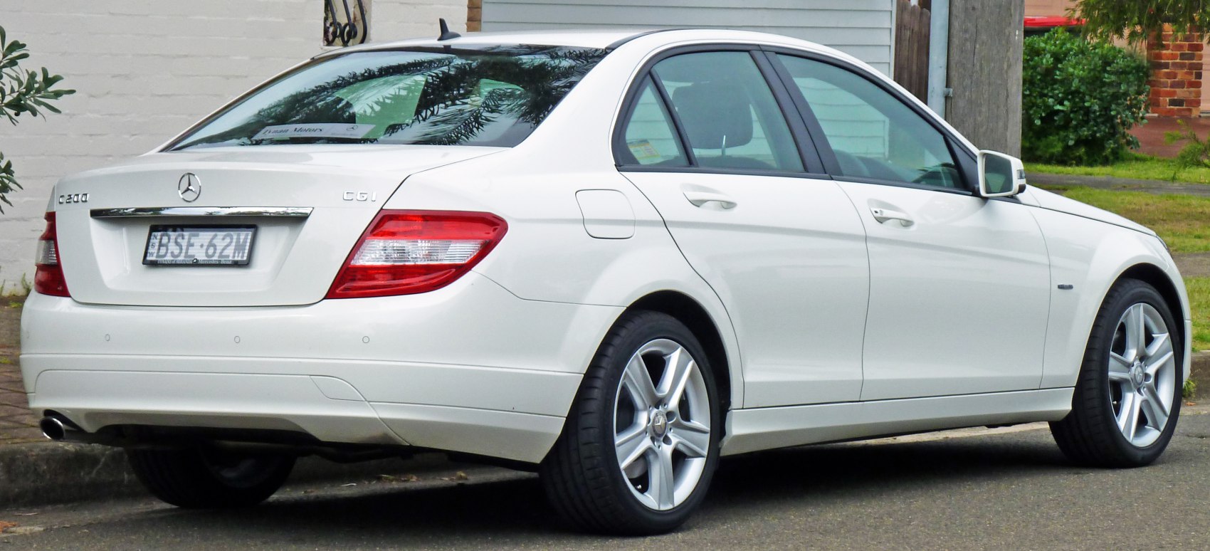 Rear side view of a white sedan with tail lights and alloy wheels
