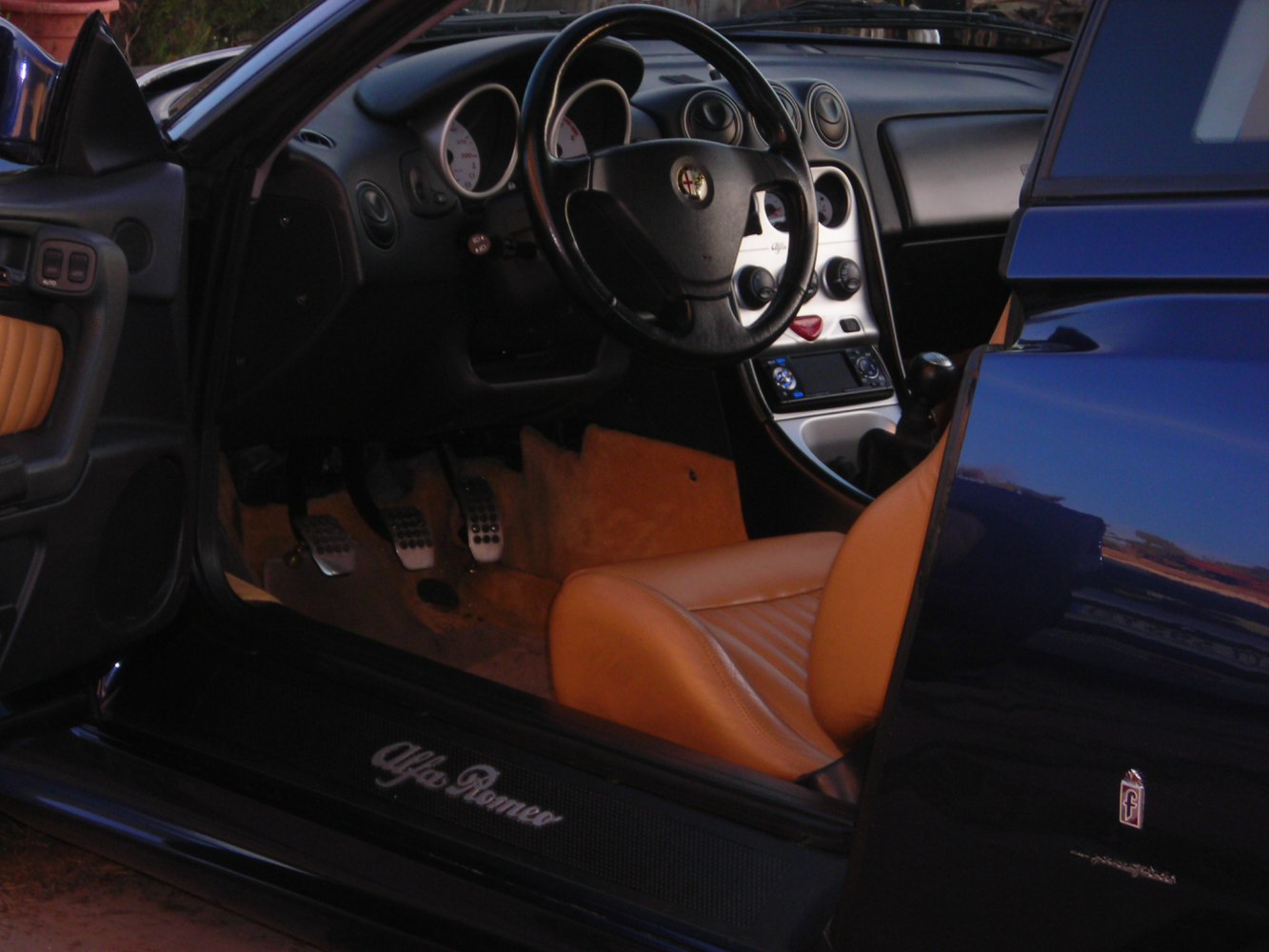 Steering wheel, dashboard, pedals, and tan leather interior seating