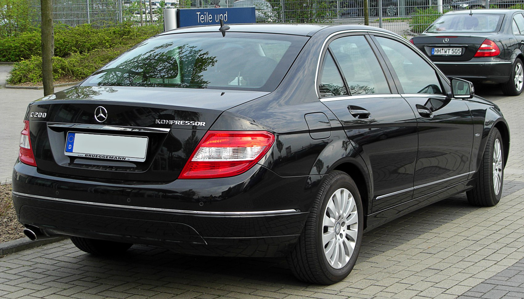 Rear view of a black sedan with distinct taillights and chrome trim
