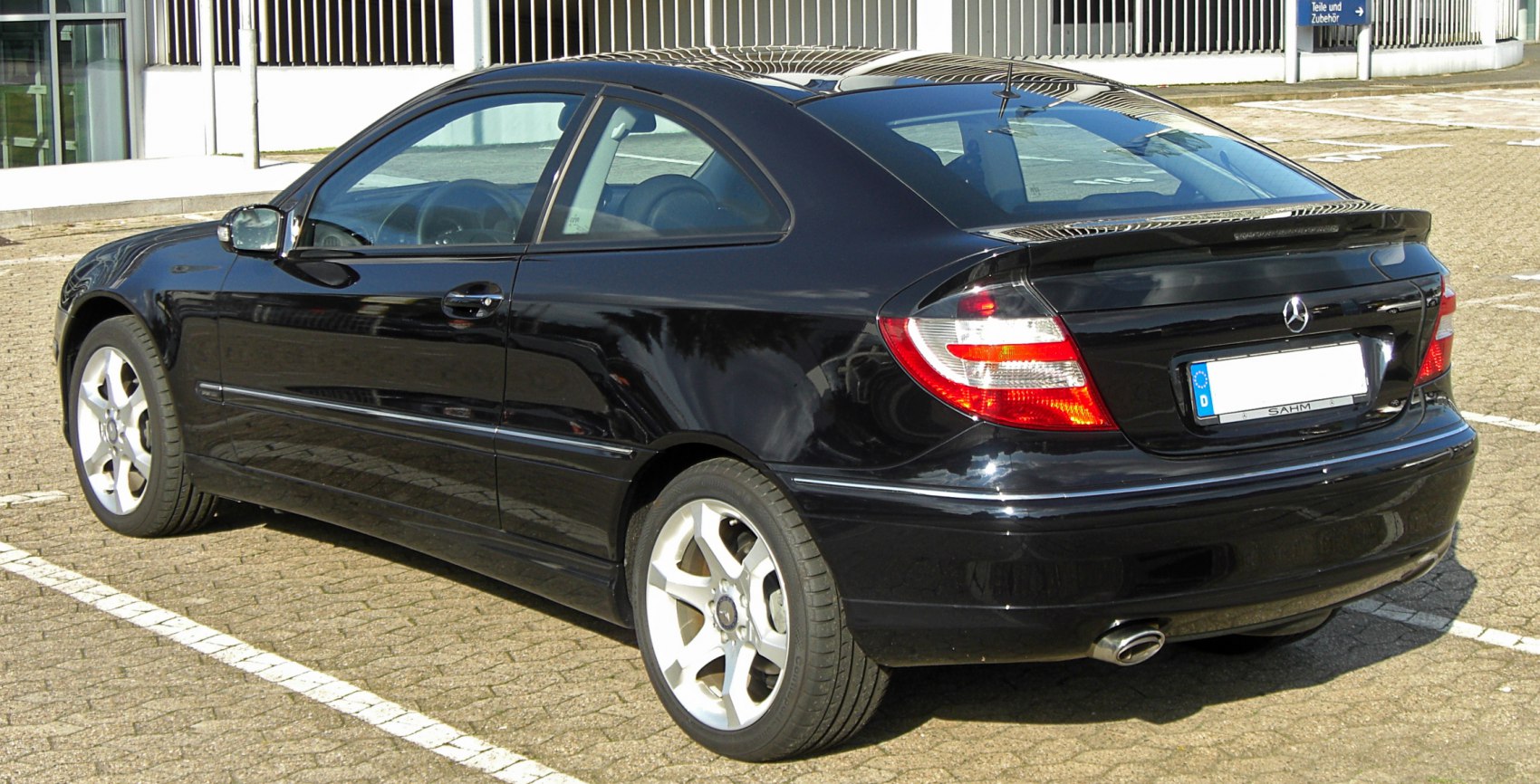 Rear side view of black two-door coupe with distinctive taillights and alloy wheels