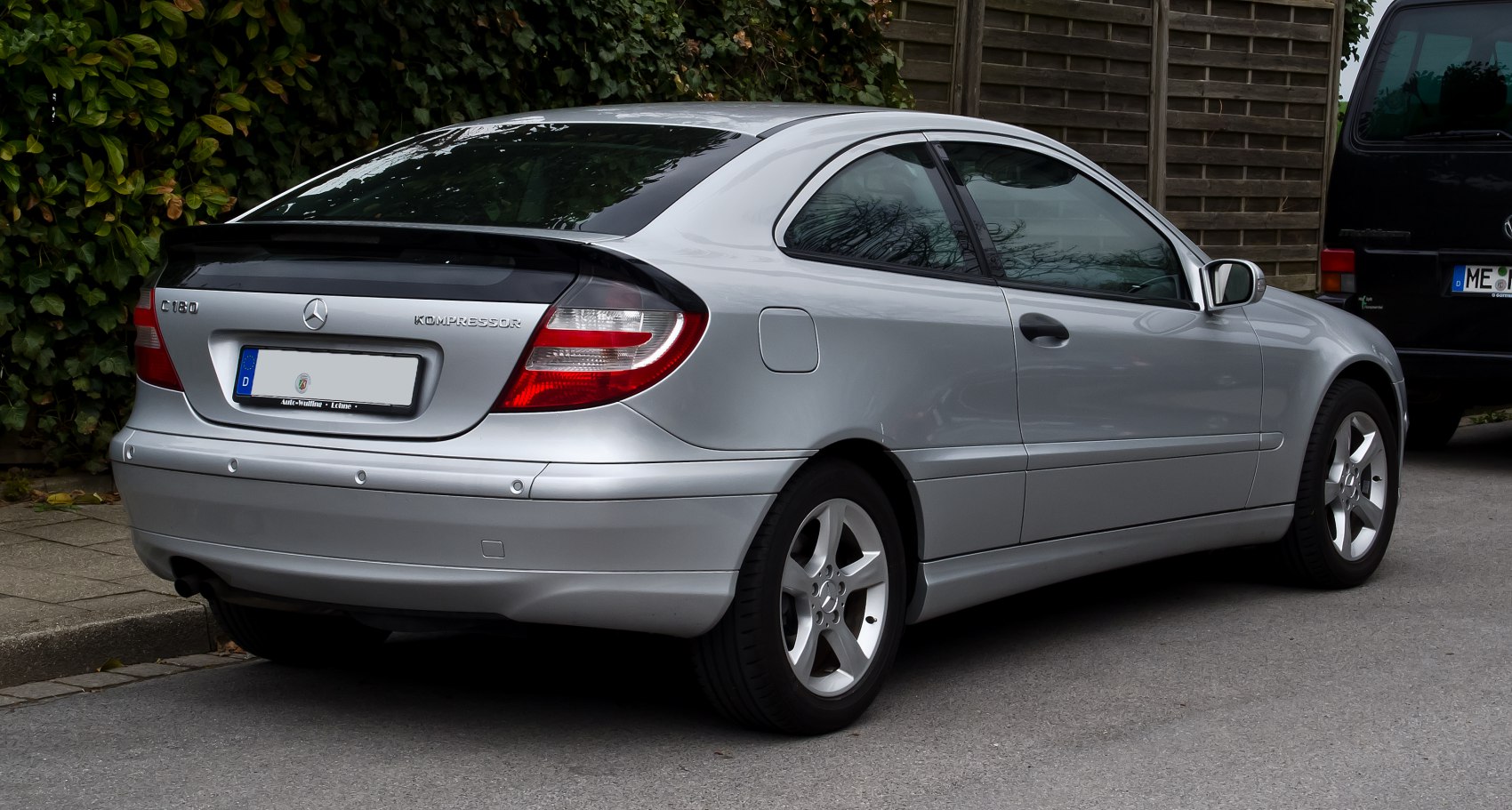 Rear-side view showcasing taillights and alloy wheels of a silver sport coupe