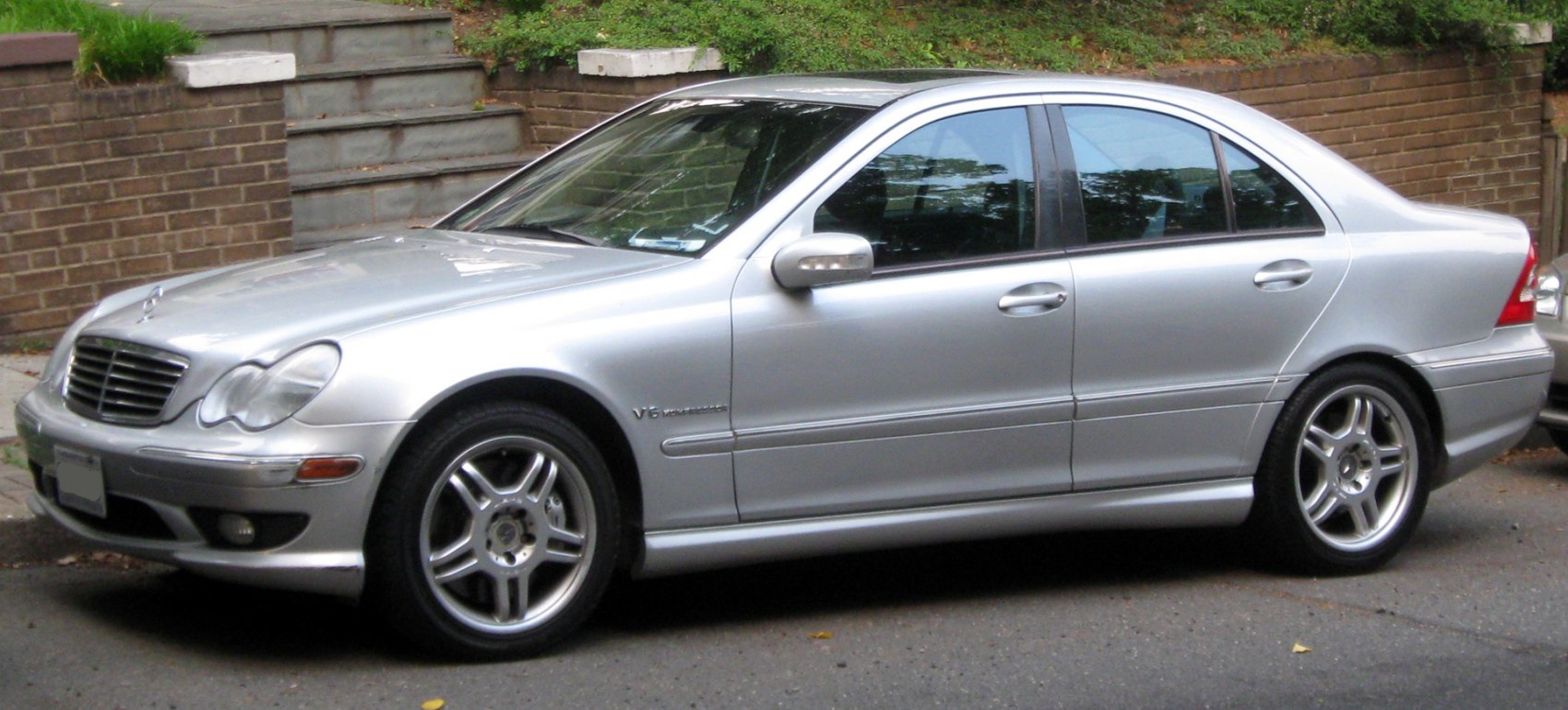 Silver sedan side profile with V6 badge and alloy wheels