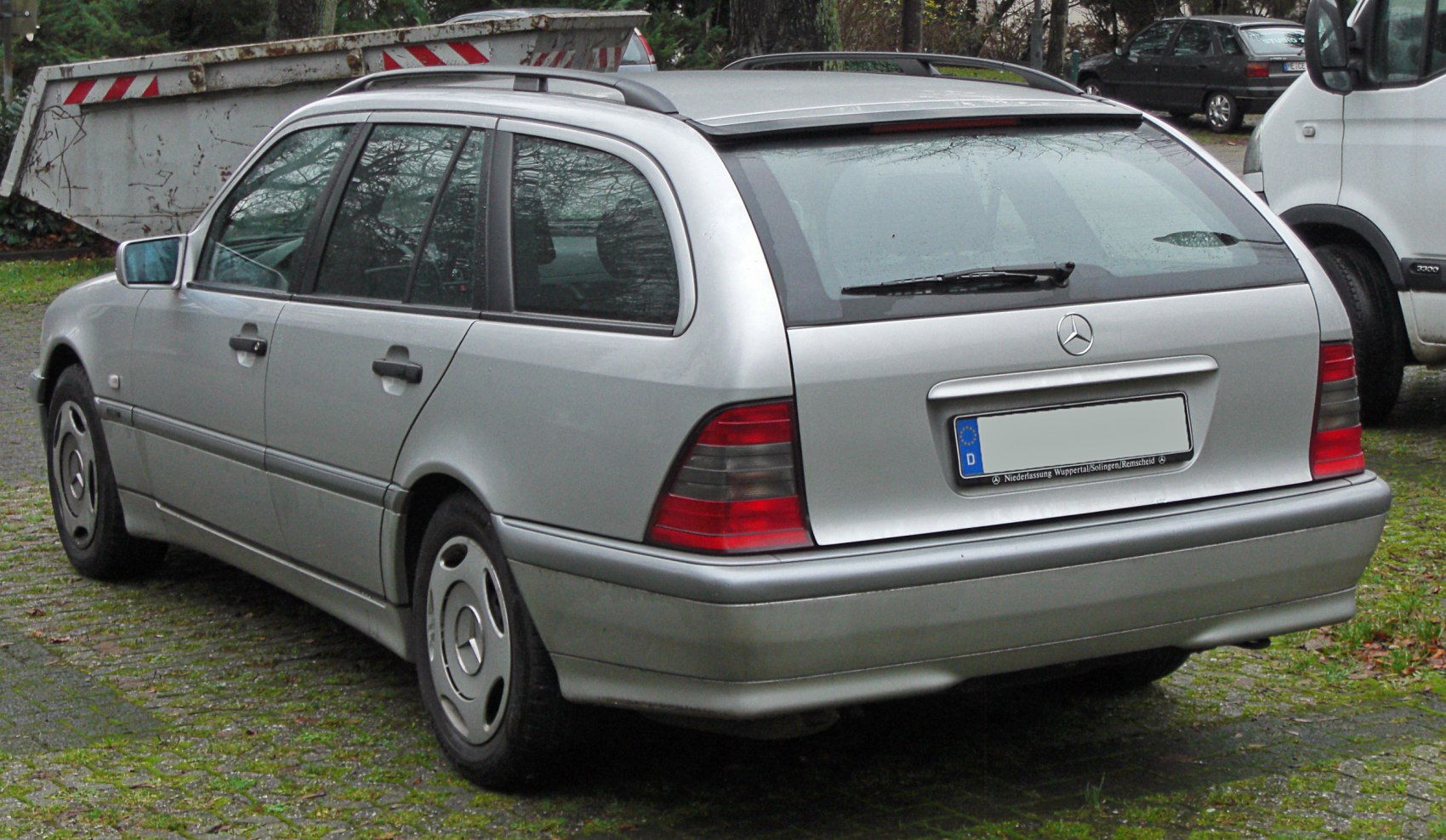 Rear side view of silver station wagon with roof rails and distinctive tail lights