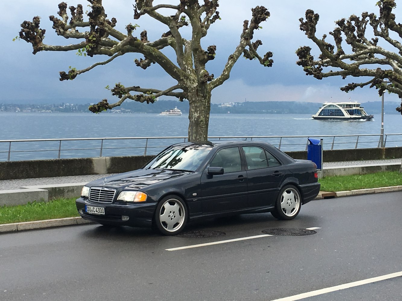 Side view of classic sedan with alloy wheels and chrome grille by waterfront