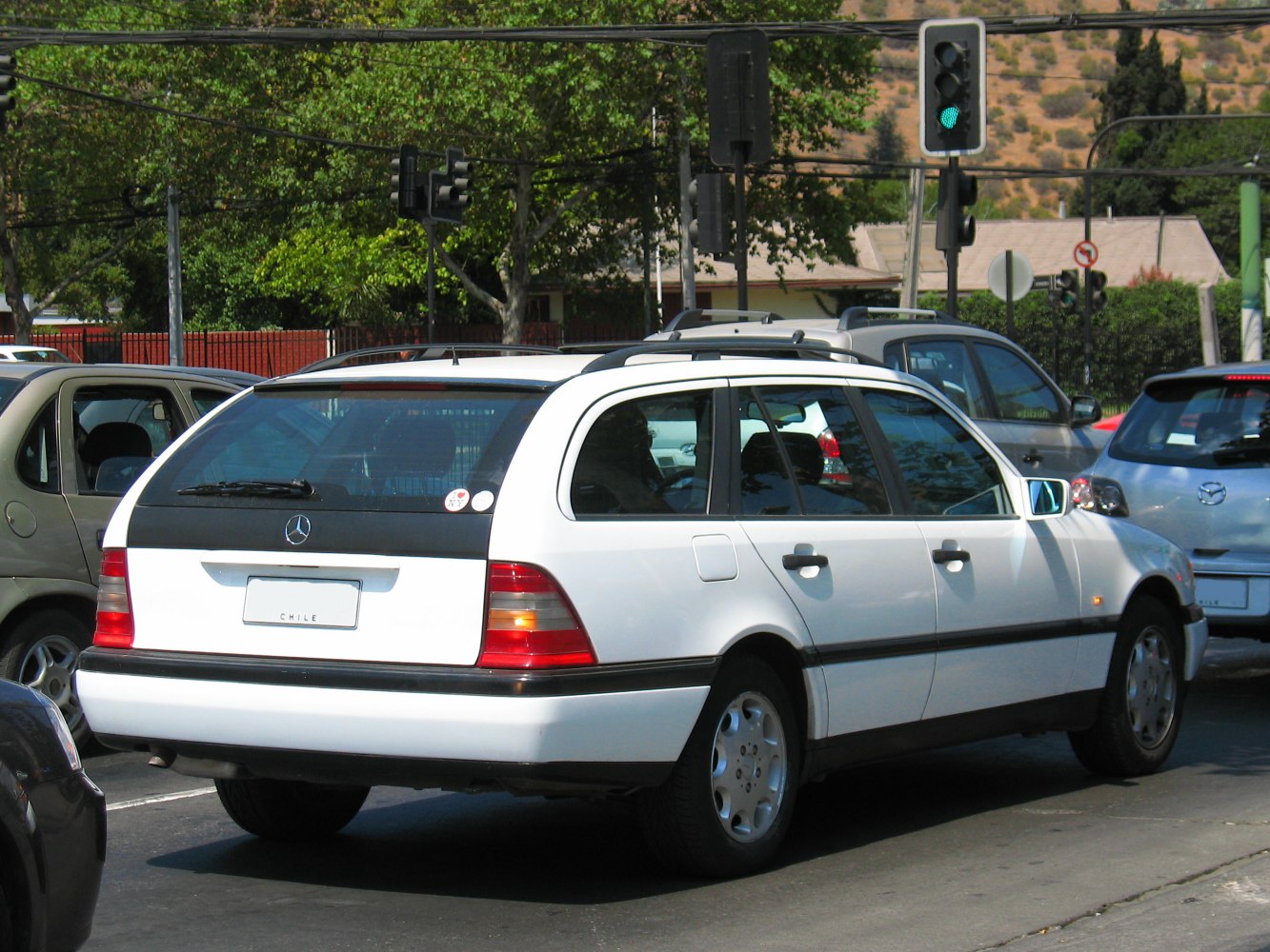 White station wagon with roof rails and rear windshield wiper in urban traffic