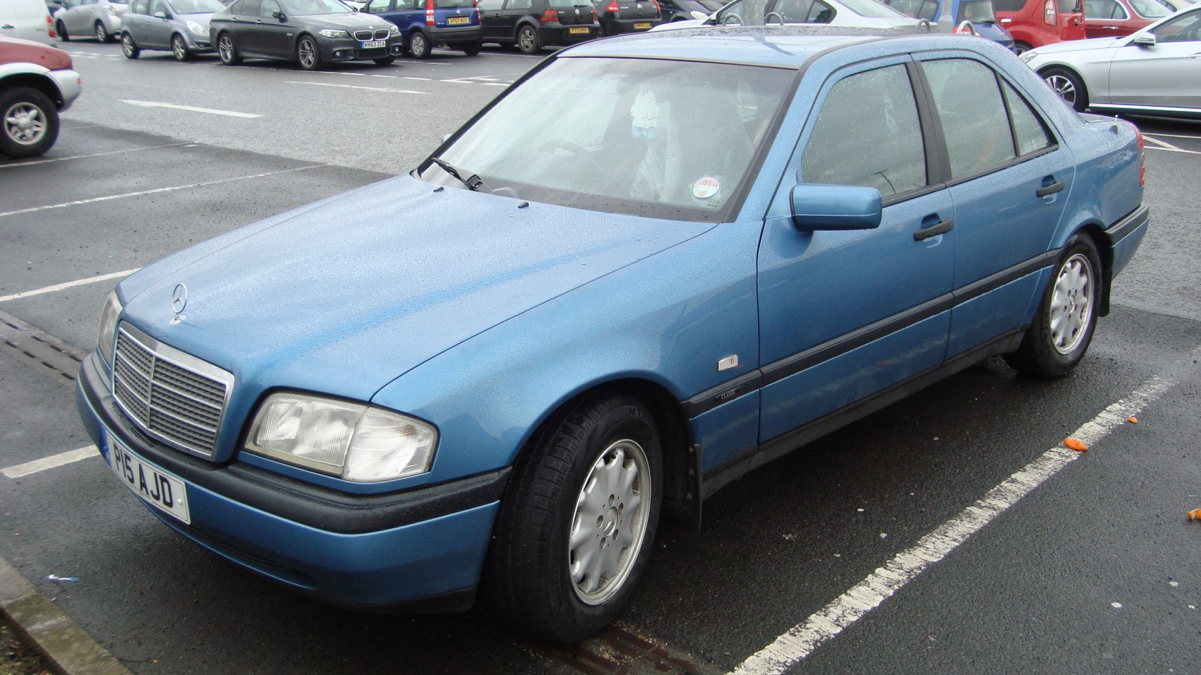 Front side view of a classic 1990s Mercedes-Benz sedan with distinctive grille and headlights