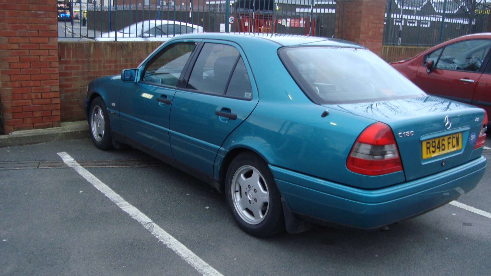 Rear side view of a 1990s sedan with alloy wheels and distinct taillights