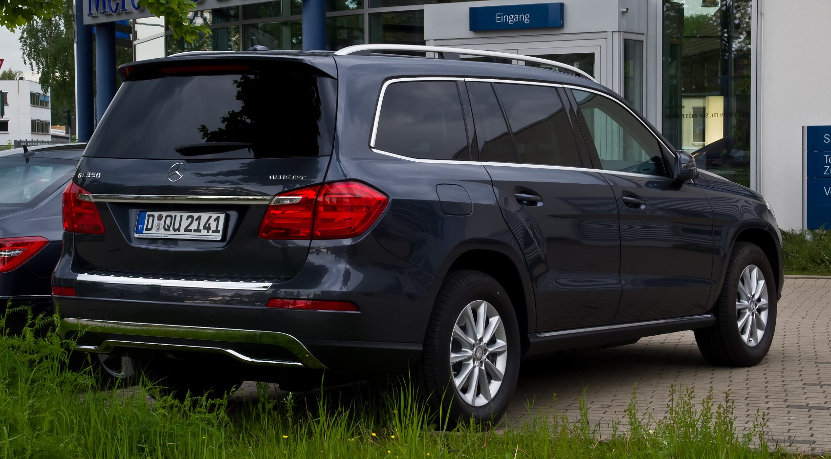 Rear view with tail lights, rear window, roof rails, and chrome trim.