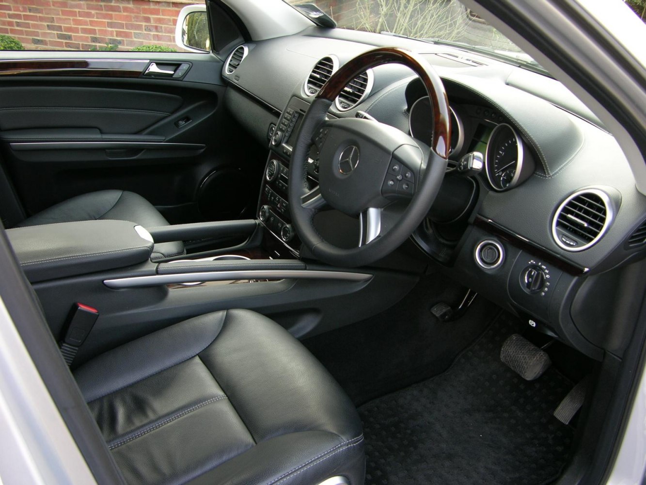 Luxury black leather interior with wood-trimmed steering wheel and detailed dashboard