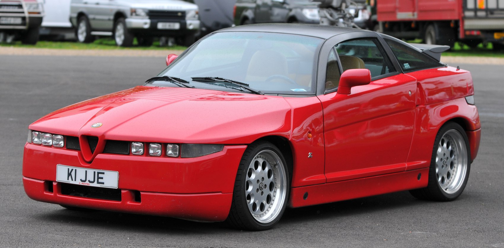 Red sports coupe with angular body, tinted roof, and rear spoiler