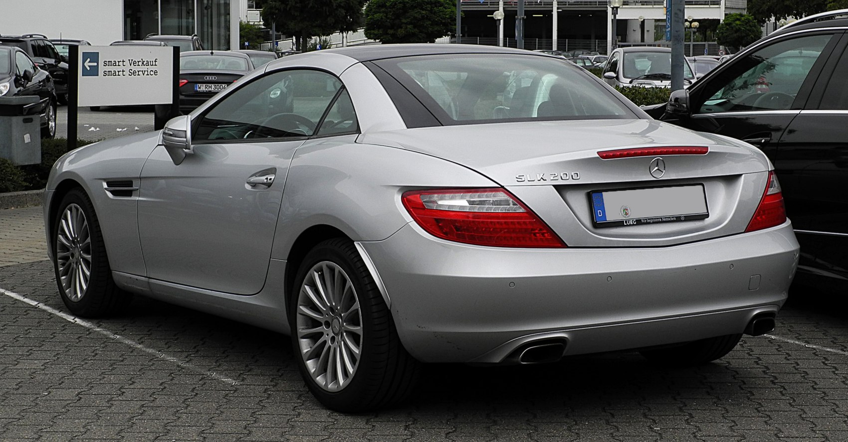 Rear side view of silver hardtop convertible with tail lights and dual exhaust