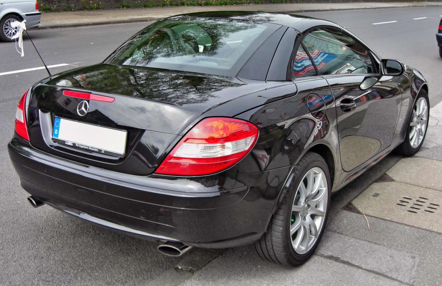 Rear view showing tail lights, dual exhaust, and alloy wheels of black coupe