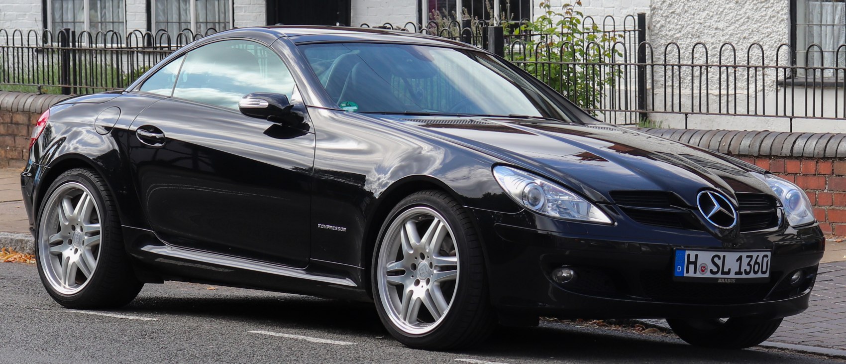 Front side view of sleek black convertible coupe with sporty alloy wheels