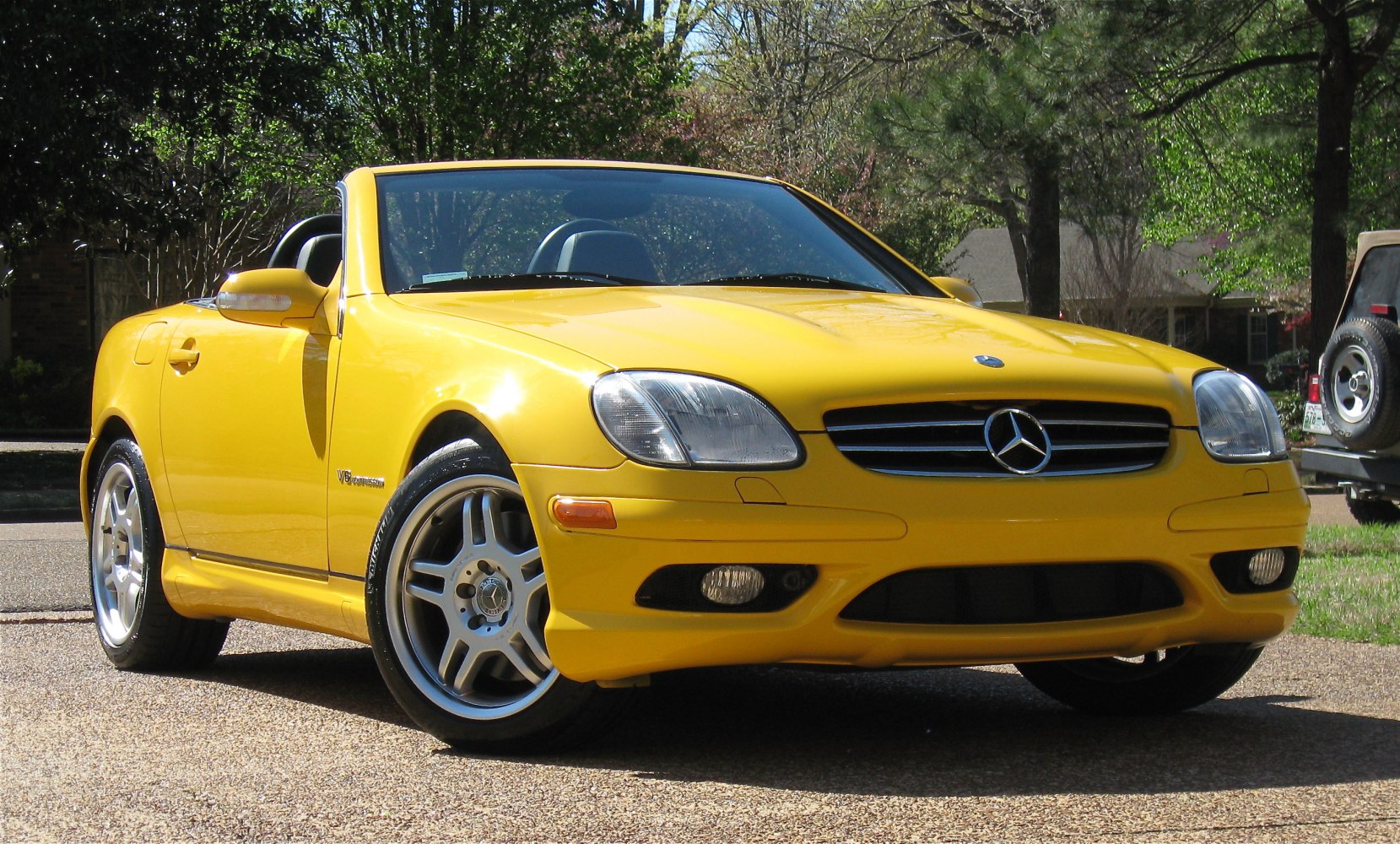 Bright yellow convertible roadster with V6 badge and alloy wheels