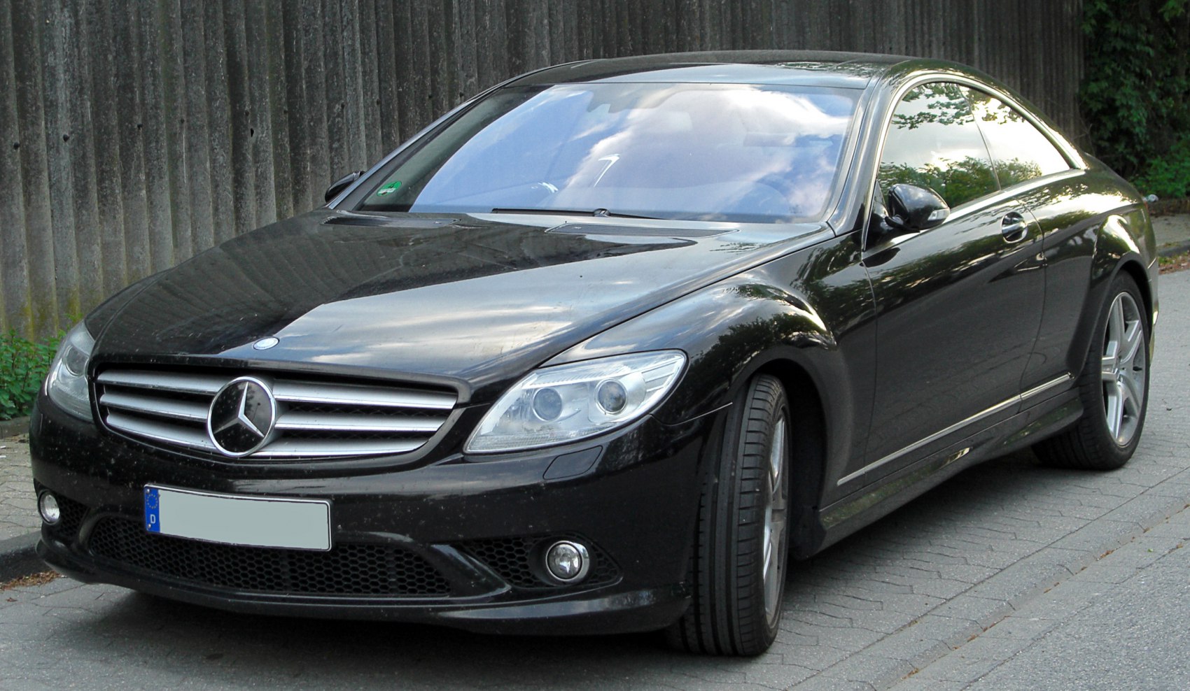 Front-side view of black luxury coupe with sleek headlights and signature grille.