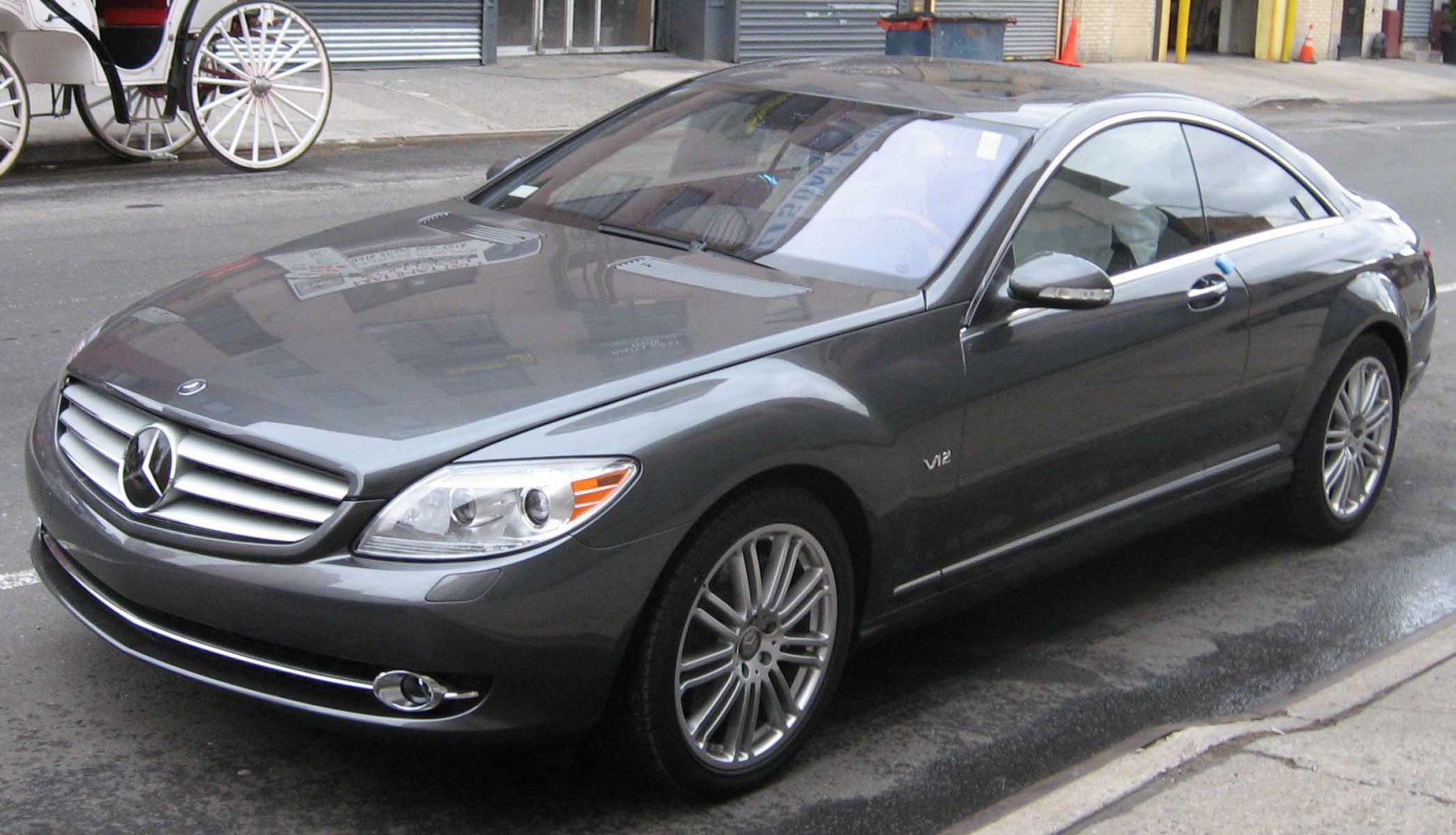 Front-side view of luxury coupe with V12 engine badge and sleek grille