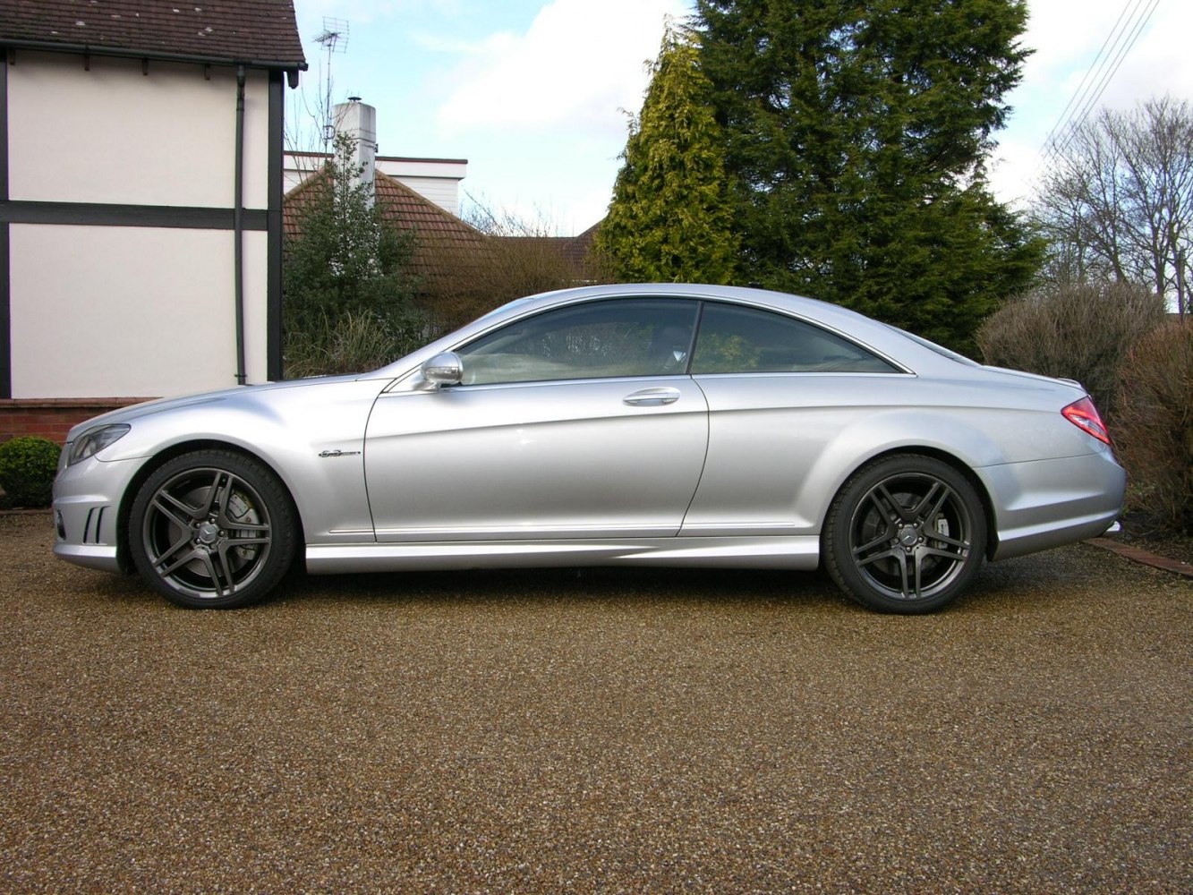 Silver luxury coupe side view with black alloy wheels and tinted windows