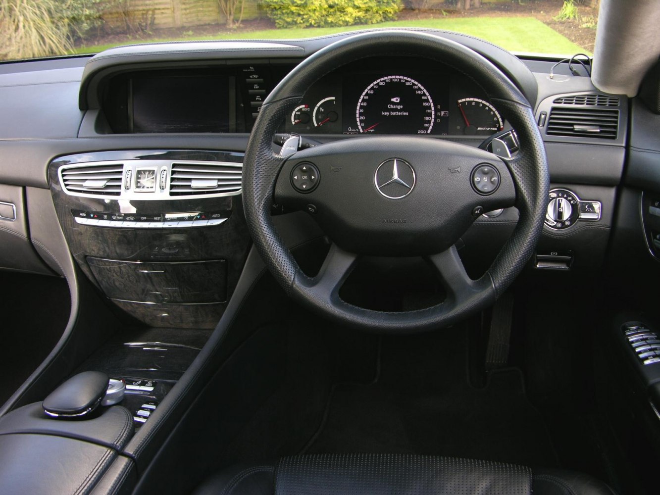 Luxury car dashboard and steering wheel with analog gauges and digital display