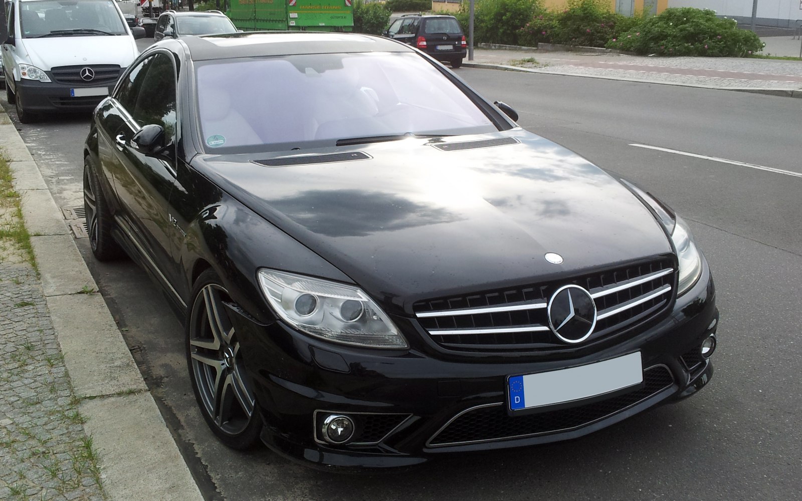 Black luxury coupe front and side view with AMG rims and V12 badge