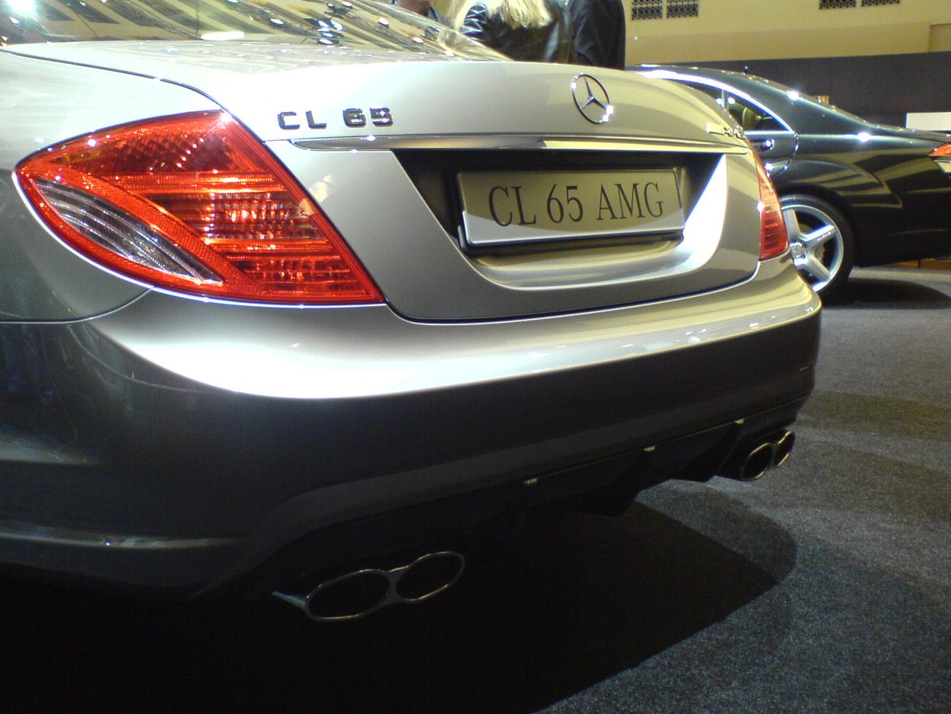 Close-up rear badge, tail light, and quad exhaust on luxury coupe