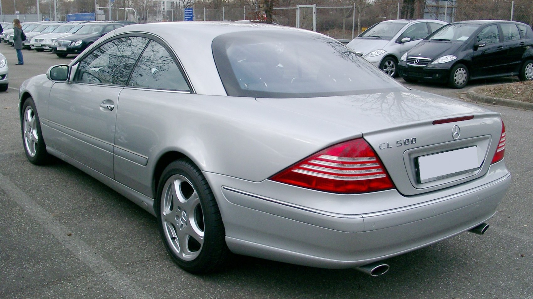 Rear and side view of a silver luxury coupe with distinctive taillights and twin exhausts.