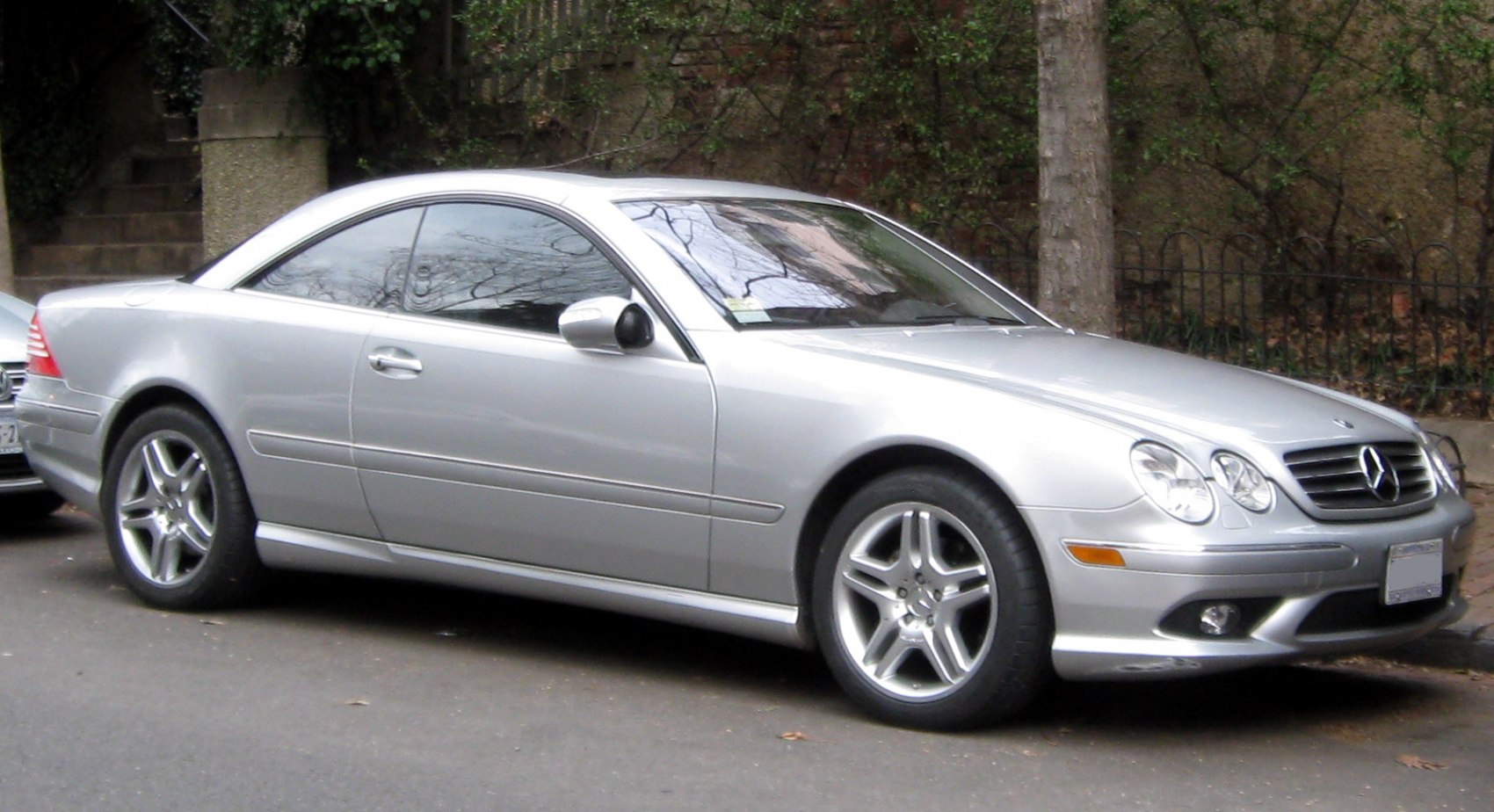 Silver luxury coupe with round headlamps and alloy wheels, side profile view