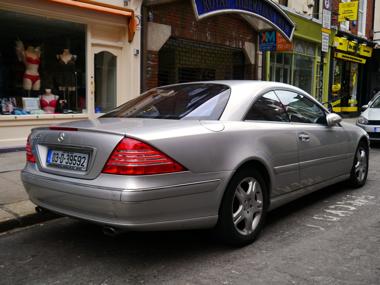 Silver luxury coupe rear side with distinctive tail lights and dual exhaust