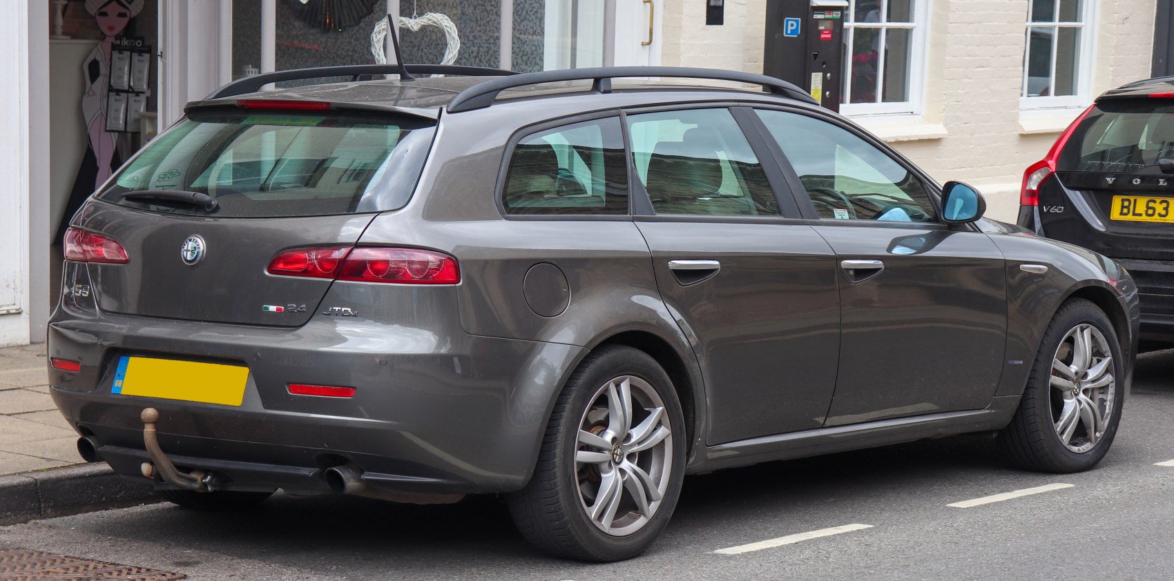 Rear side view of grey station wagon with distinctive taillights and roof rails