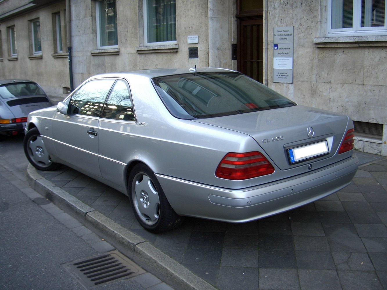 Silver luxury coupe rear with V12 badge and classic tail lights