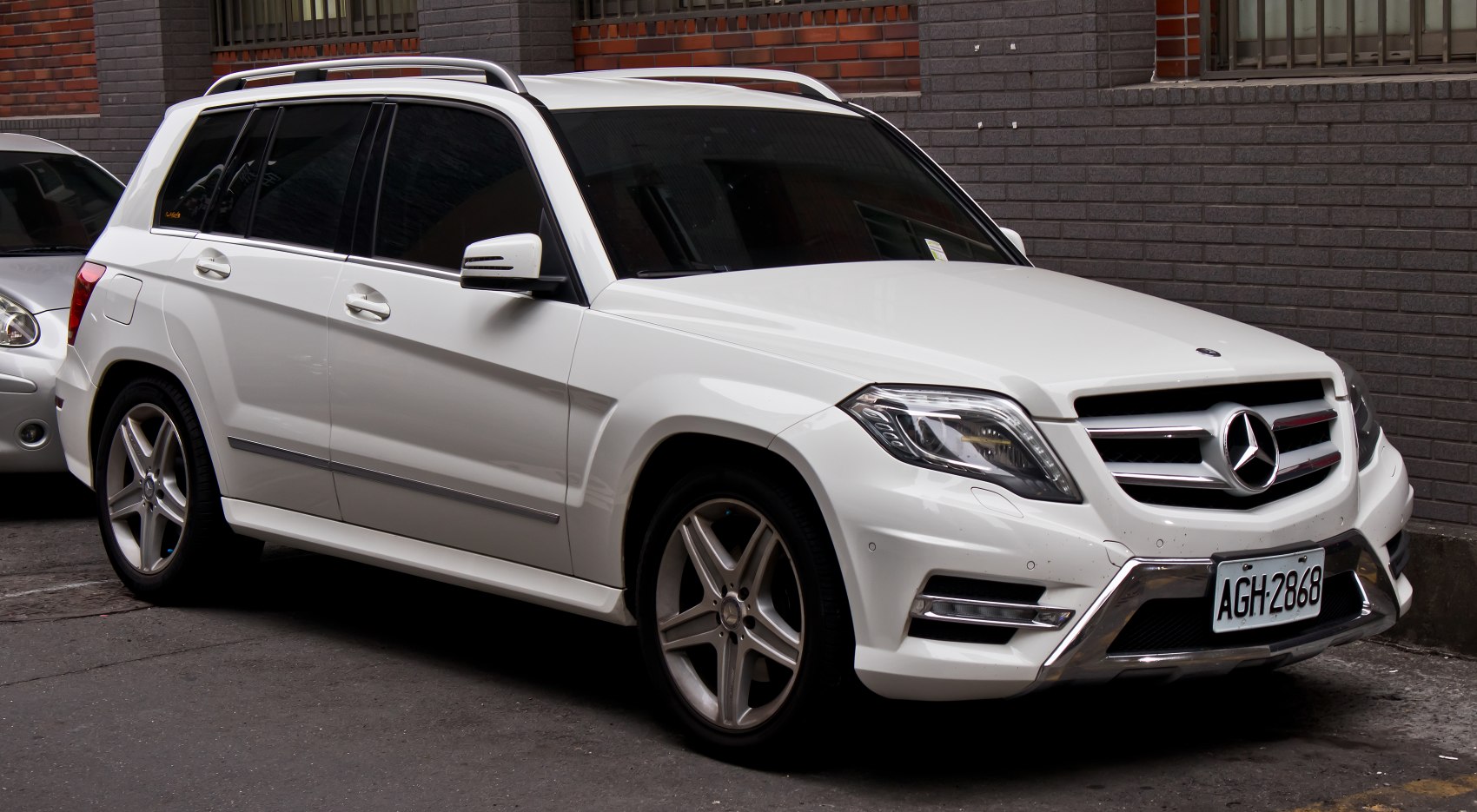 Front side view of white luxury SUV with alloy wheels and bold grill