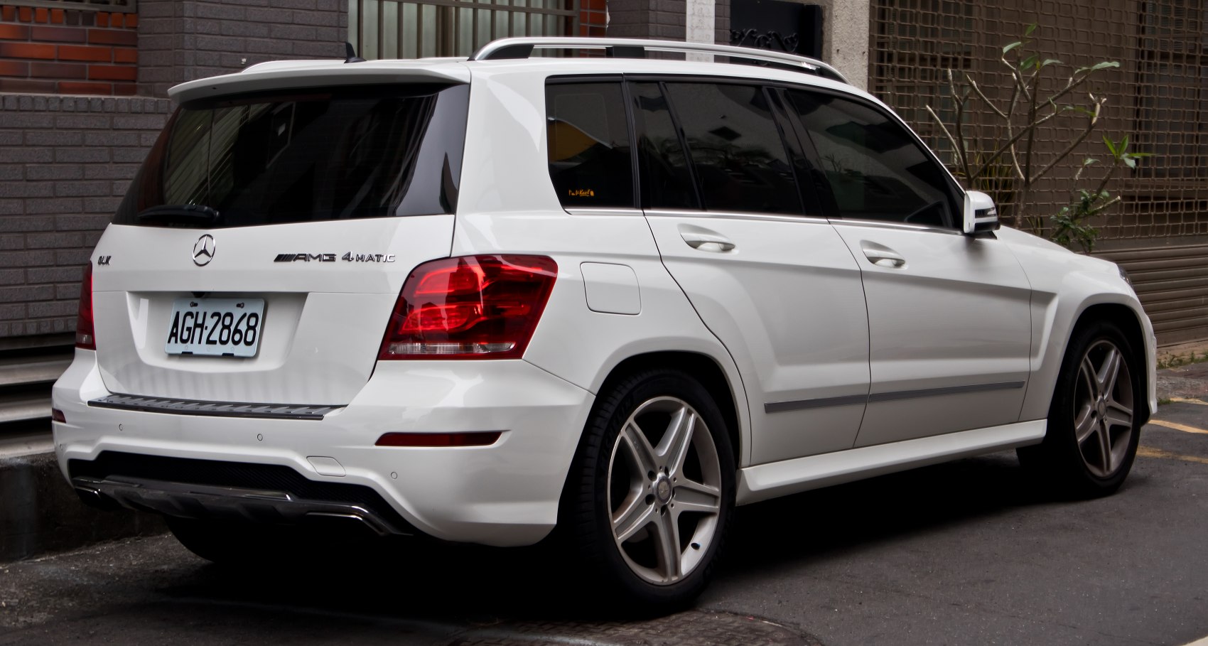 Rear view of a white SUV with AMG 4MATIC badge and roof rails