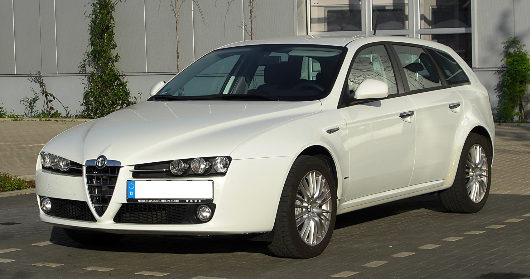 Front side view of a white station wagon with distinctive headlights and grille