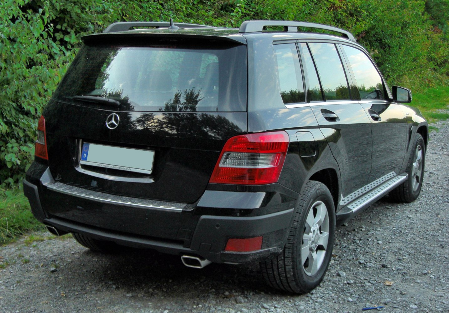 Rear view with tail lights, dual exhaust, side steps, and roof rails