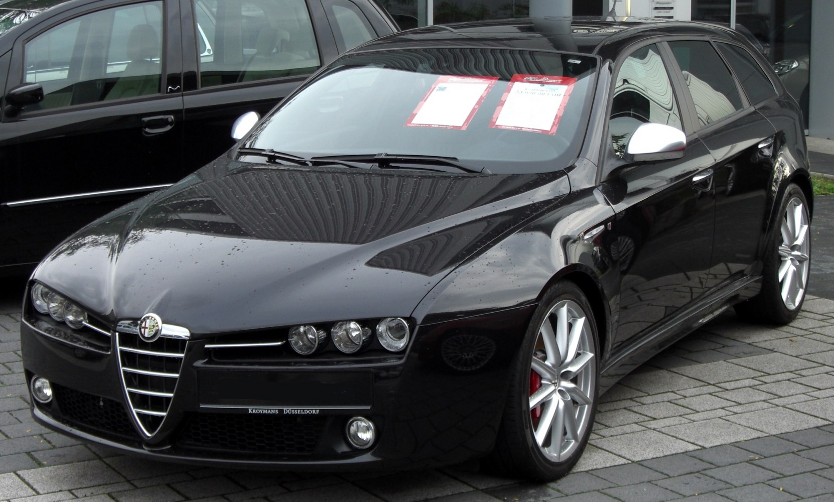 Front angled view of sleek black vehicle with alloy wheels and signature front grille